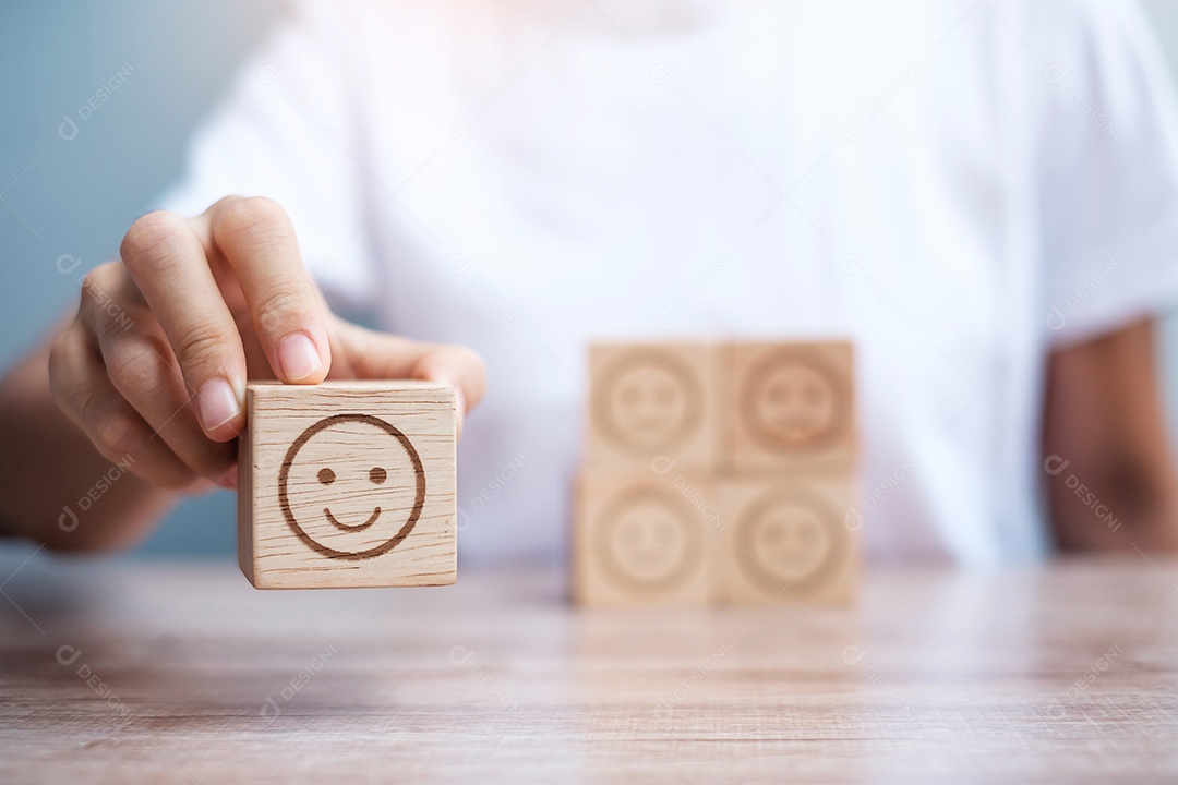 Mão de homem segurando o bloco de rosto de emoção. Cliente escolhe Emoticon