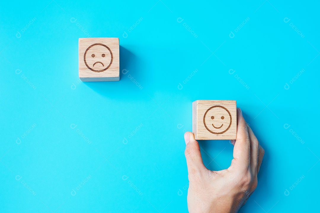 Mão de homem segurando o bloco de rosto de emoção. Cliente escolhe emojis