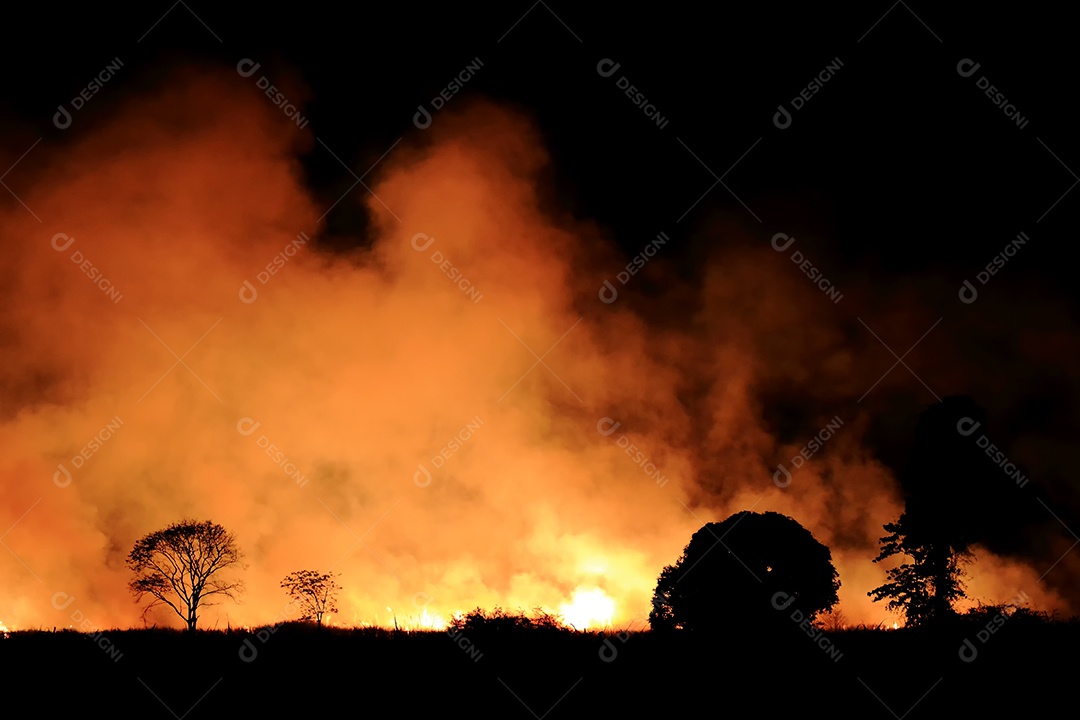 O fogo queimando fumaça laranja e vermelha encheu o céu à noite.