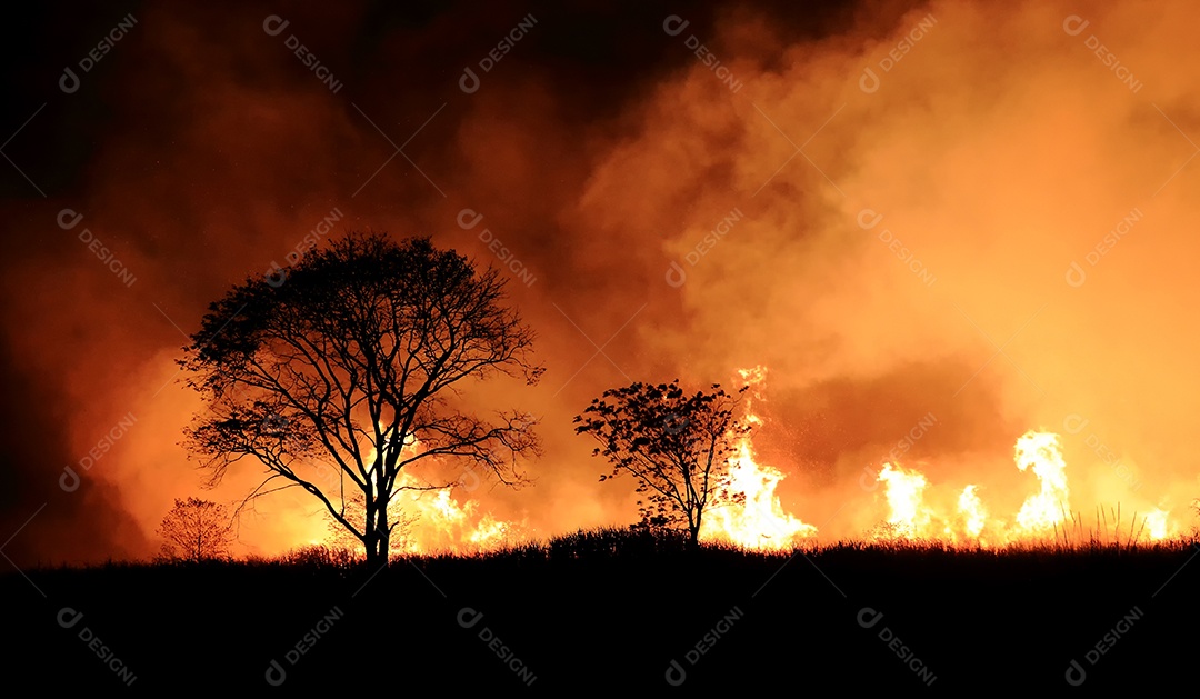 O fogo queimando fumaça laranja e vermelha encheu o céu à noite.