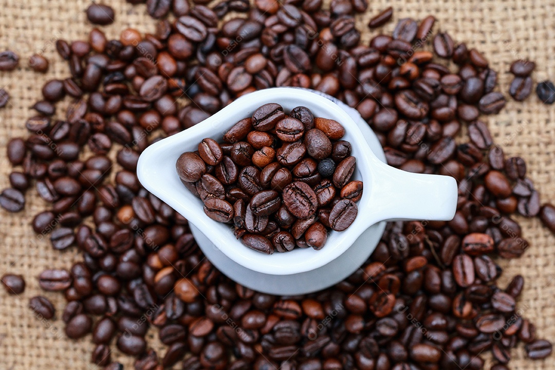 Grãos de café e uma xícara em termos de moda de saco.