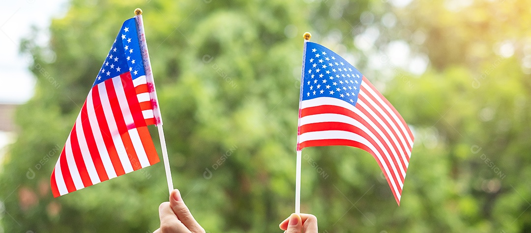 mão segurando a bandeira dos Estados Unidos da América no fundo do céu azul