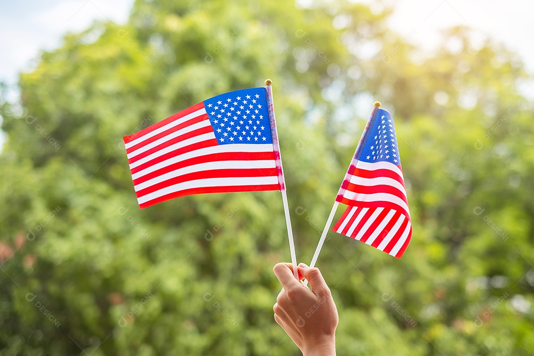 mão segurando a bandeira dos Estados Unidos da América no fundo do céu azul