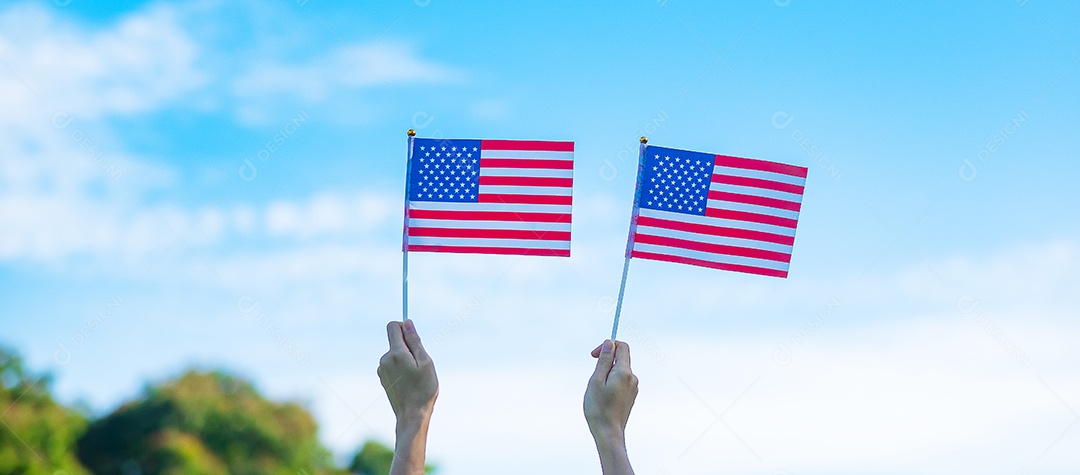 mão segurando a bandeira dos Estados Unidos da América no fundo do céu azul