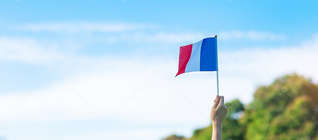 mão segurando a bandeira da França sobre fundo de céu azul