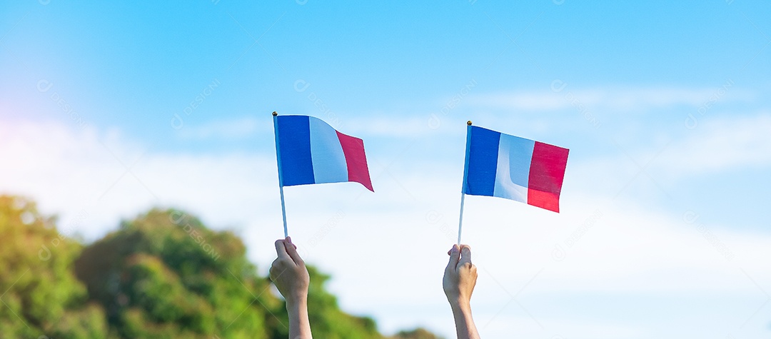 mão segurando a bandeira da França sobre fundo de céu azul