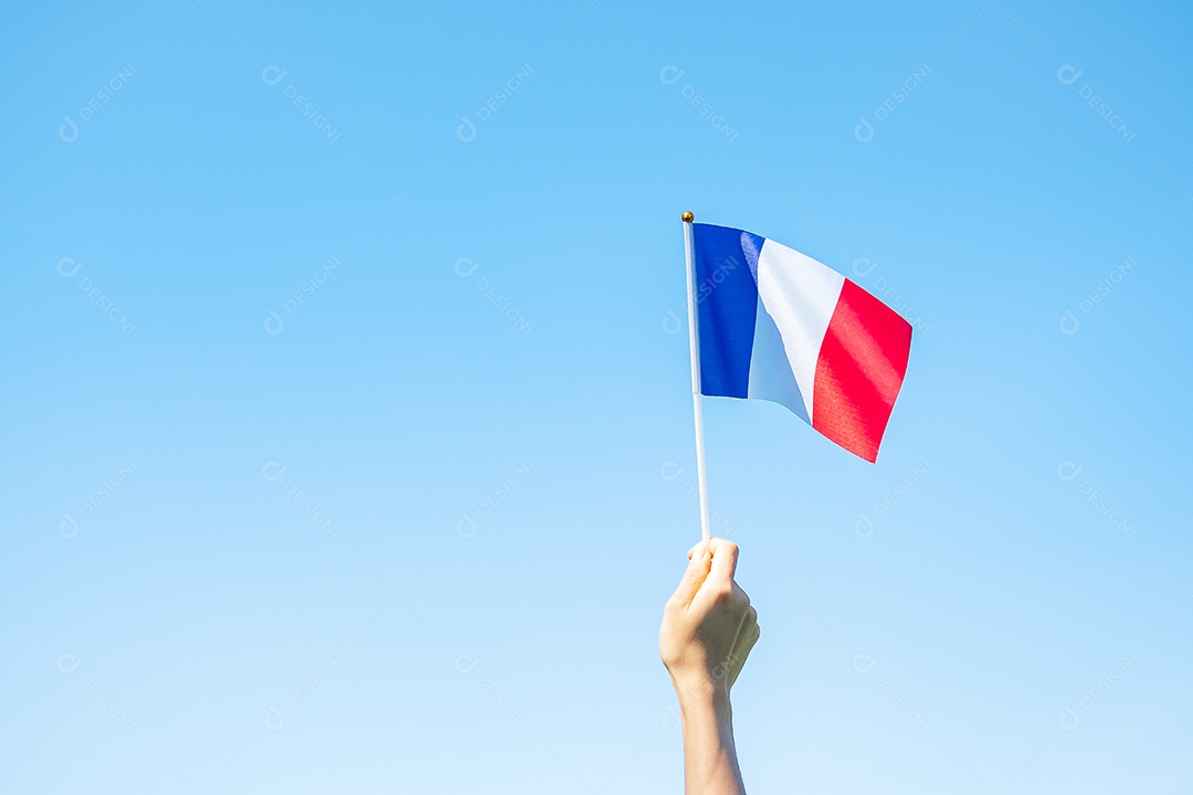 mão segurando a bandeira da França sobre fundo de céu azul
