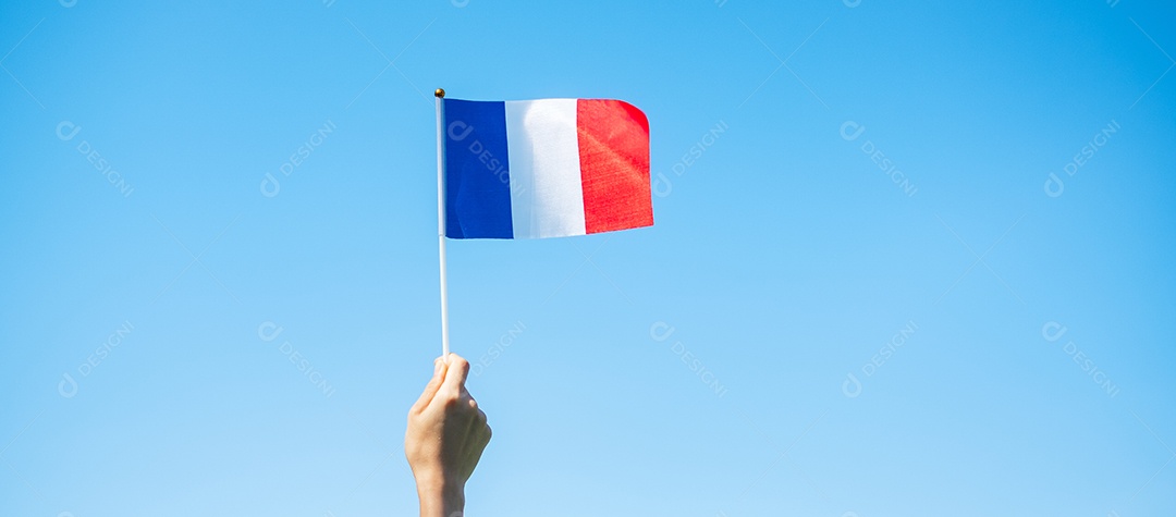 mão segurando a bandeira da França sobre fundo de céu azul