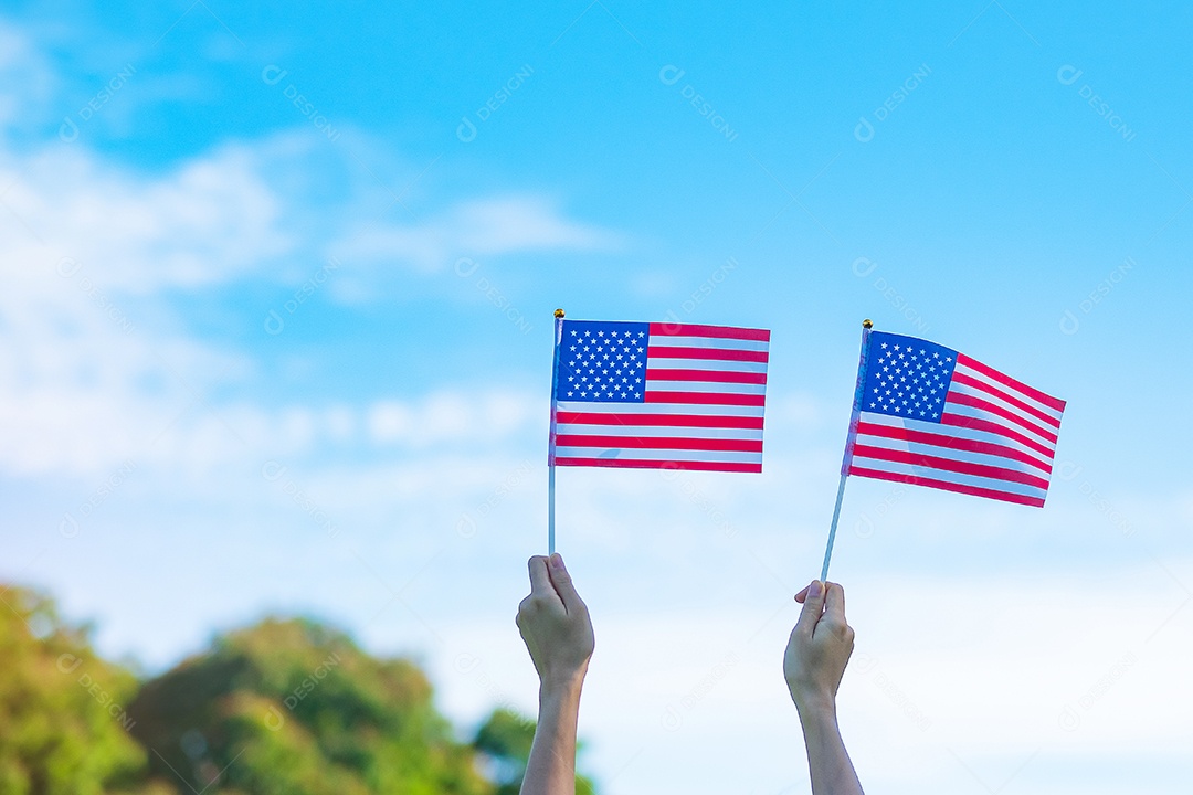 mão segurando a bandeira dos Estados Unidos da América no fundo do céu azul