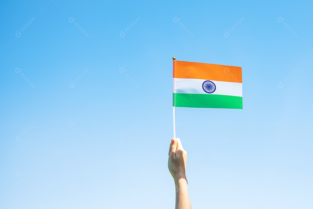 mão segurando a bandeira da Índia no fundo do céu azul.
