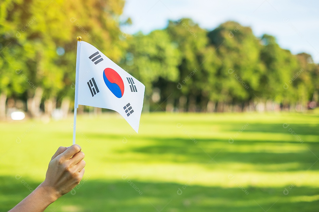 Mão segurando a bandeira da Coreia no fundo da natureza. Fundação Nacional.