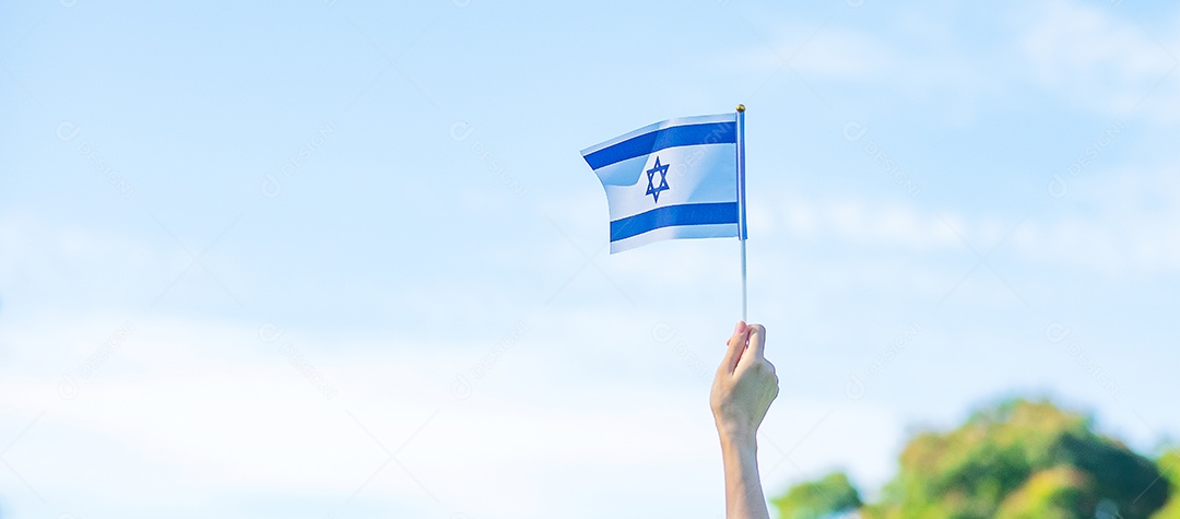Mão segurando a bandeira de Israel no fundo da natureza.