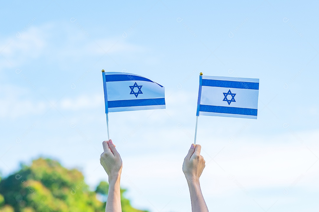 Mão segurando a bandeira de Israel no fundo da natureza.