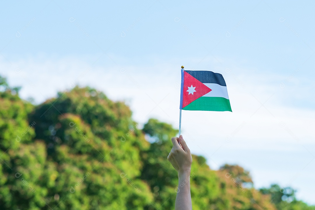 Mão segurando a bandeira da Jordânia no fundo da natureza. Jordânia Independente.