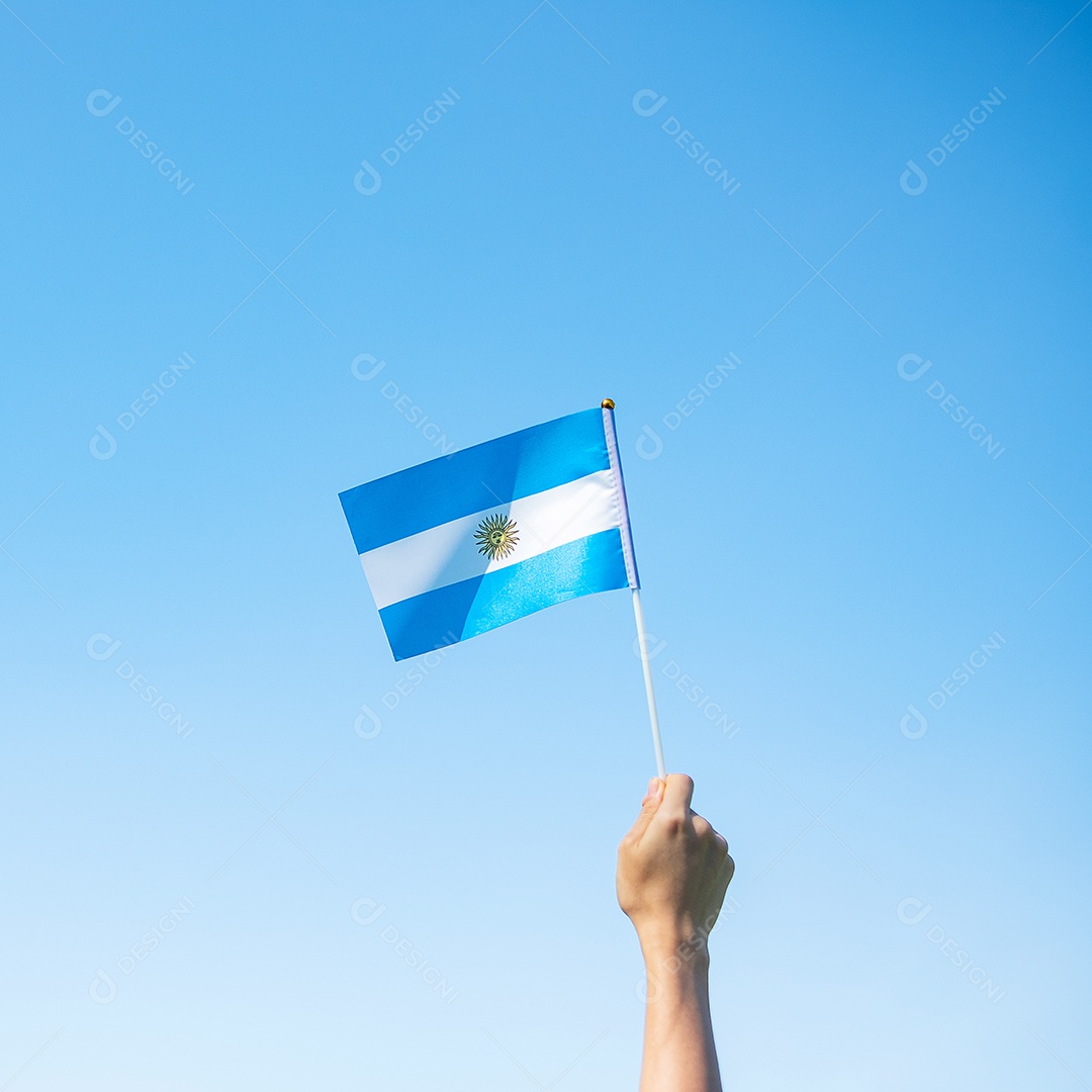 Mão segurando a bandeira da Argentina no fundo da natureza.