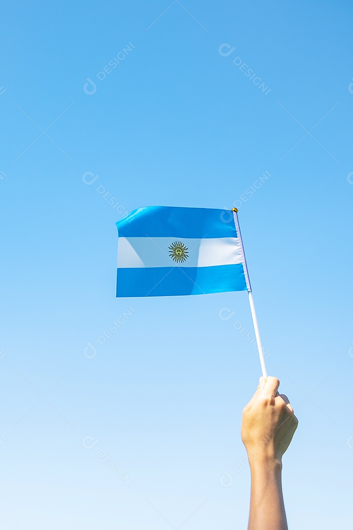 Mão segurando a bandeira da Argentina no fundo da natureza.