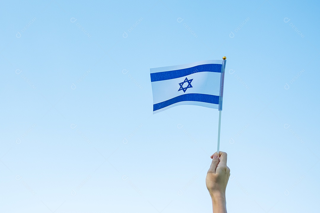 Mão segurando a bandeira de Israel no fundo da natureza.