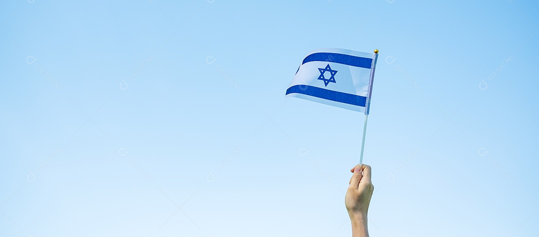 Mão segurando a bandeira de Israel no fundo da natureza.