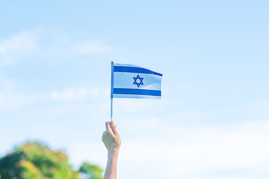 Mão segurando a bandeira de Israel no fundo da natureza.