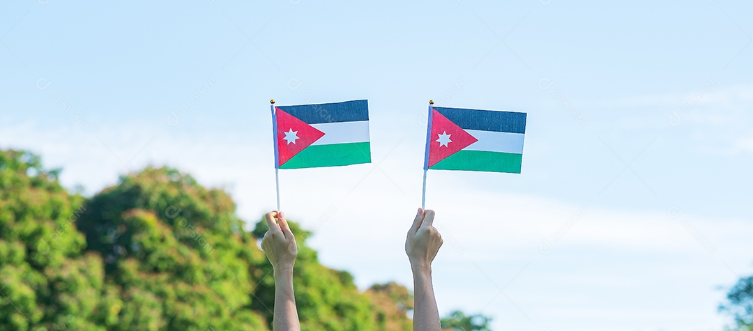 Mão segurando a bandeira da Jordânia no fundo da natureza. Jordânia Independente.