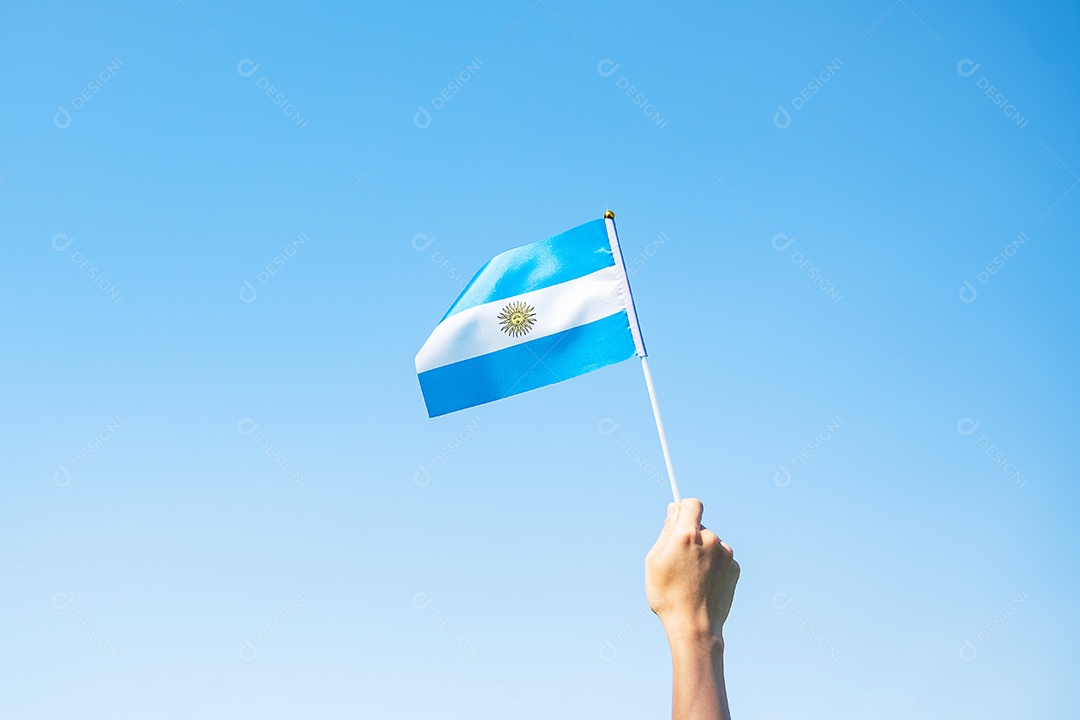 Mão segurando a bandeira da Argentina no fundo da natureza.