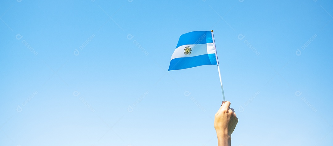Mão segurando a bandeira da Argentina no fundo da natureza.