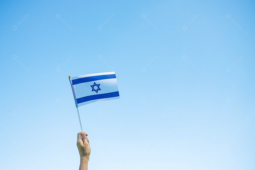 Mão segurando a bandeira de Israel no fundo da natureza.