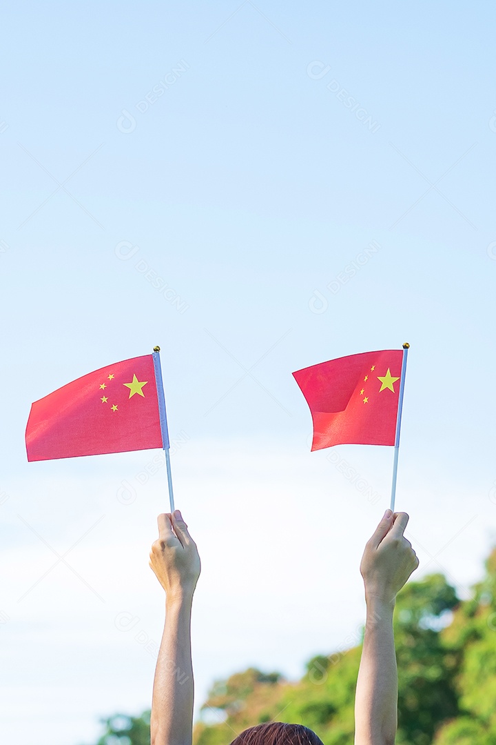 Mão segurando a bandeira da China no fundo do céu azul. Dia Nacional.