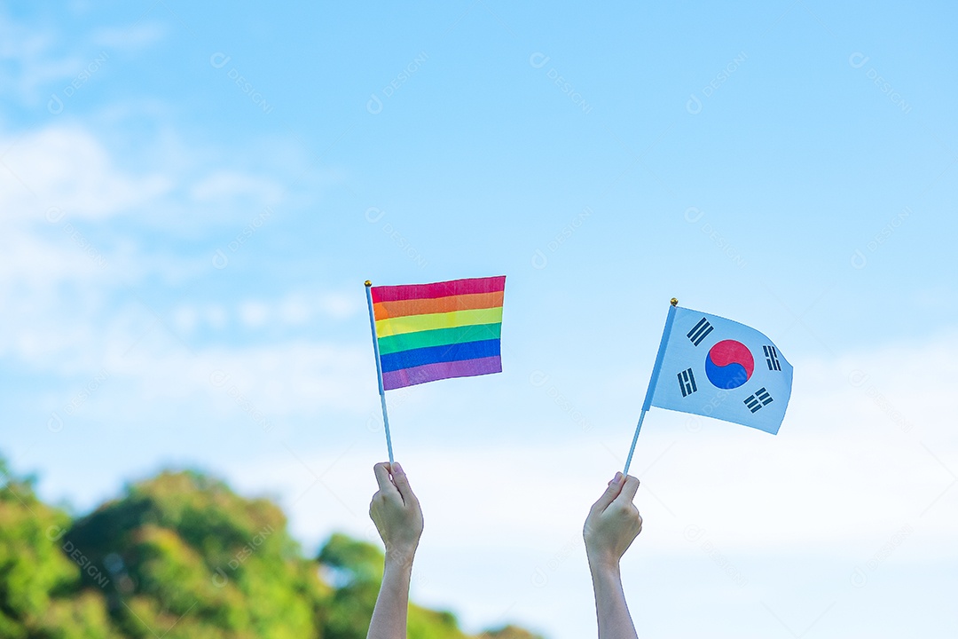Mãos mostrando a bandeira LGBTQ Arco-íris e Coreia no fundo da natureza.