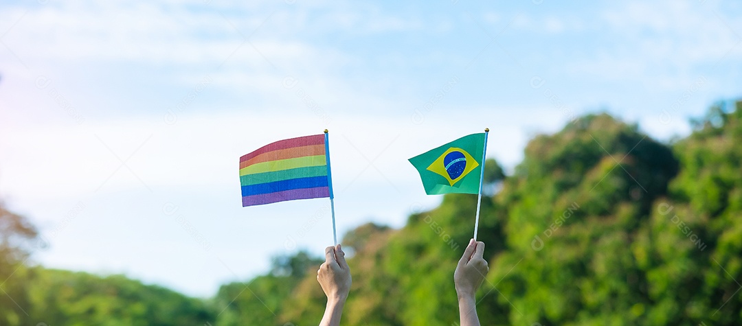 Mãos mostrando LGBTQ Arco-íris e bandeira do Brasil no fundo da natureza.