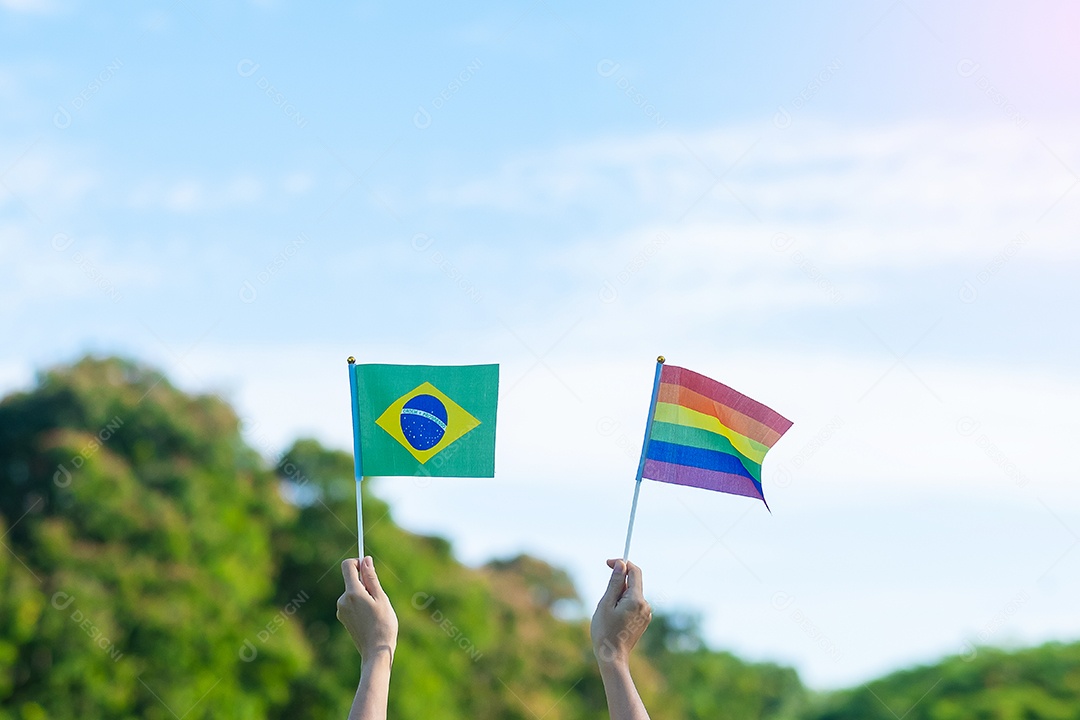 Mãos mostrando LGBTQ Arco-íris e bandeira do Brasil no fundo da natureza.