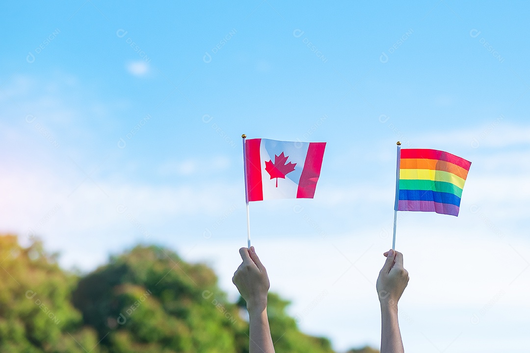 Mãos mostrando LGBTQ Arco-íris e bandeira do Canadá no fundo da natureza.