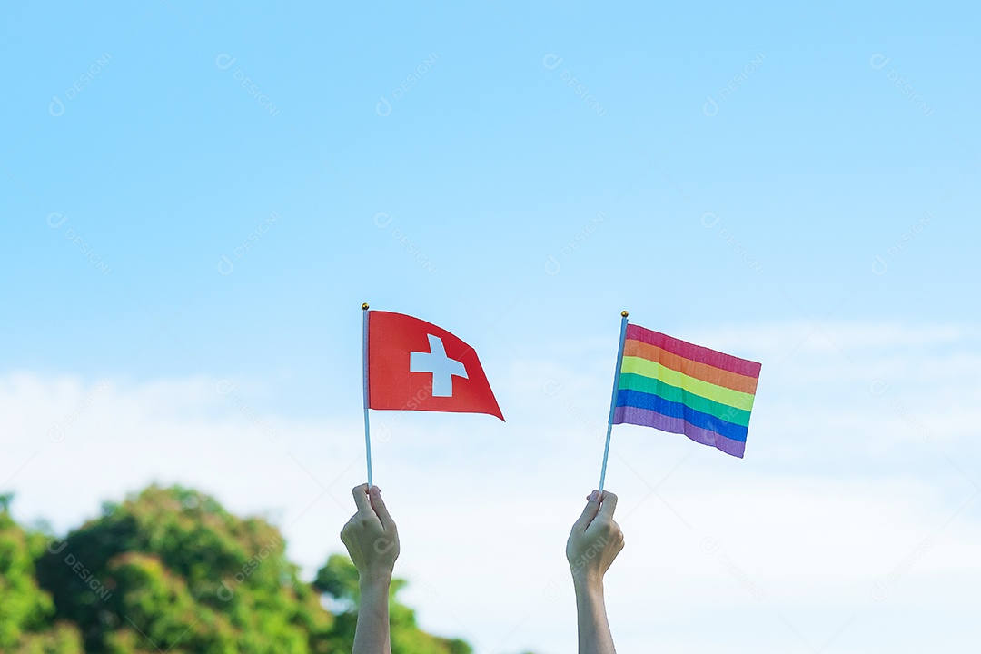 Mãos mostrando LGBTQ Arco-íris e bandeira da Suíça no fundo da natureza.