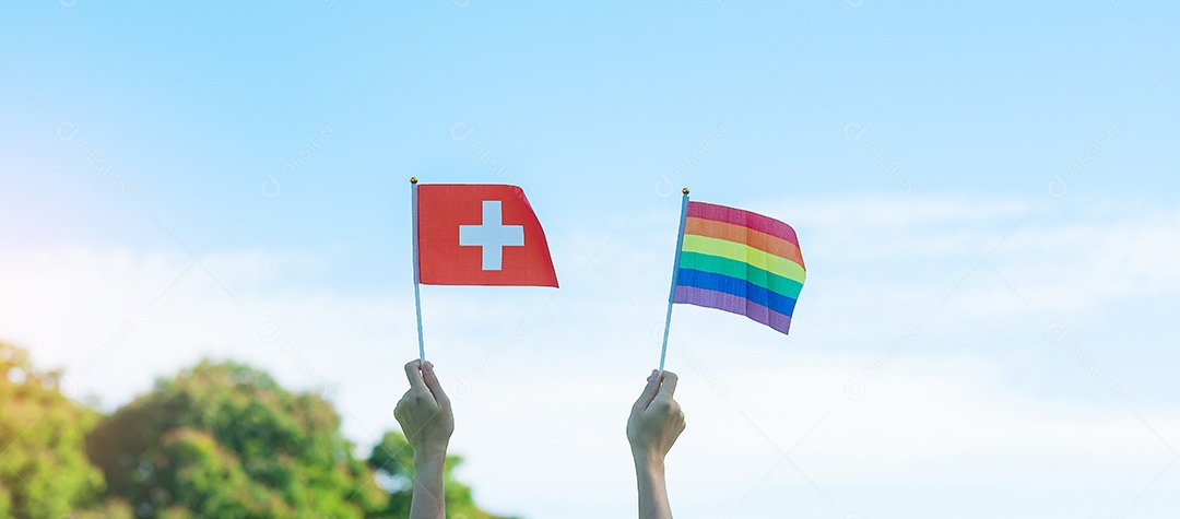 Mãos mostrando LGBTQ Arco-íris e bandeira da Suíça no fundo da natureza.