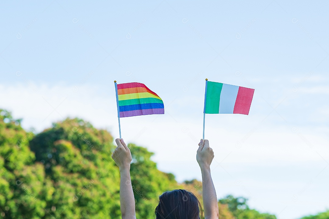 Hands showing LGBTQ rainbow and Italy flag on nature background.