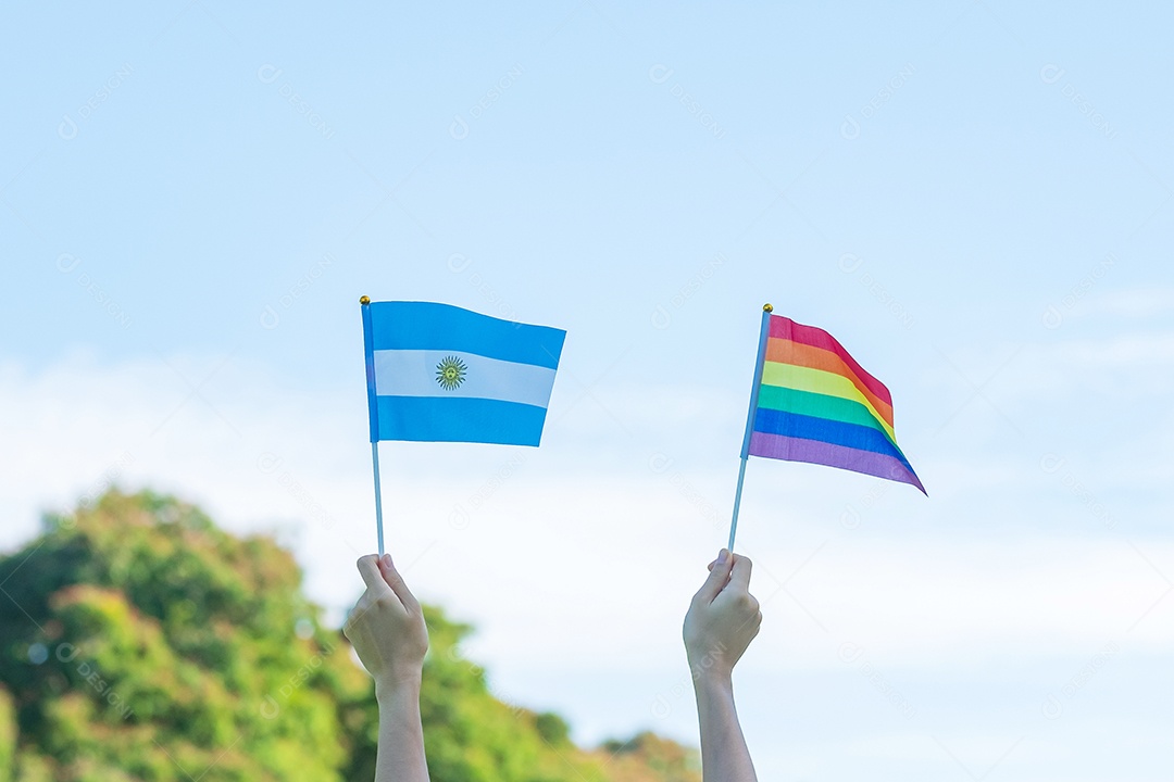 Mãos mostrando LGBTQ Arco-íris e bandeira Argentina no fundo da natureza.