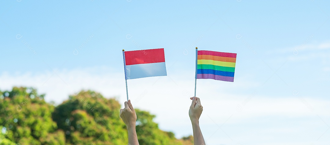 Mãos mostrando LGBTQ Arco-íris e bandeira da Indonésia no fundo da natureza.