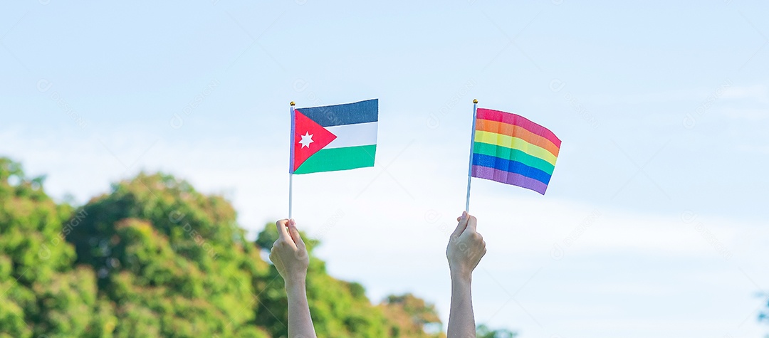 Mãos mostrando a bandeira LGBTQ Arco-Íris e Jordan no fundo da natureza.
