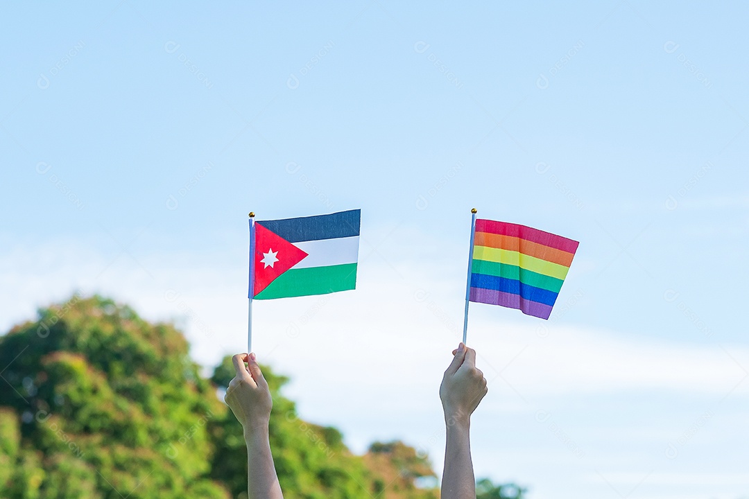 Hands showing LGBTQ Rainbow and Jordan flag on nature background.