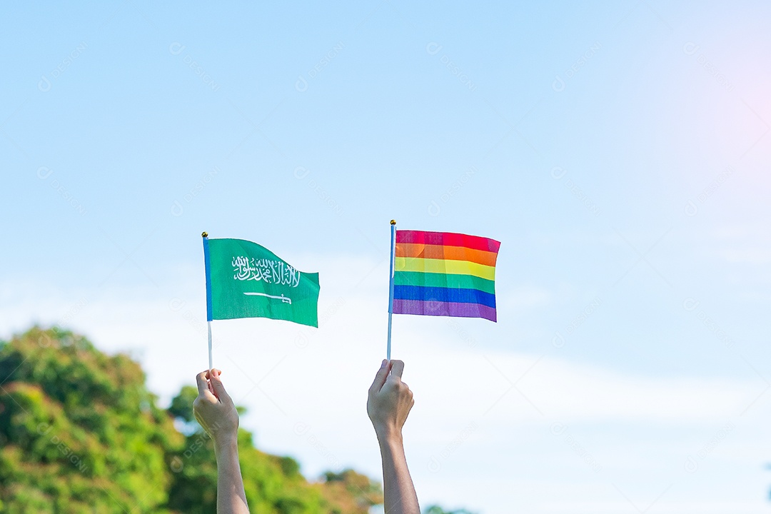 Mãos mostrando LGBTQ  Arco-íris e bandeira da Arábia Saudita no fundo da natureza.