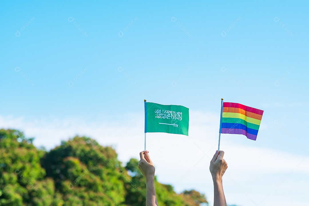 Mãos mostrando LGBTQ  Arco-íris e bandeira da Arábia Saudita no fundo da natureza.