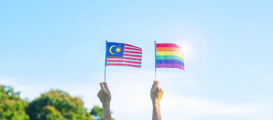 Mãos mostrando LGBTQ Arco-íris e bandeira da Malásia no fundo da natureza.