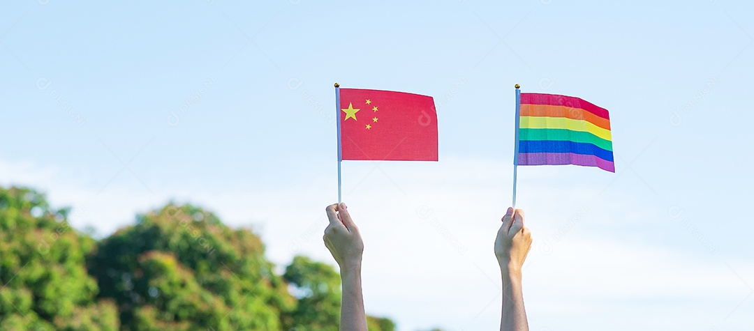 Mãos mostrando LGBTQ Arco-íris e bandeira da China no fundo da natureza.