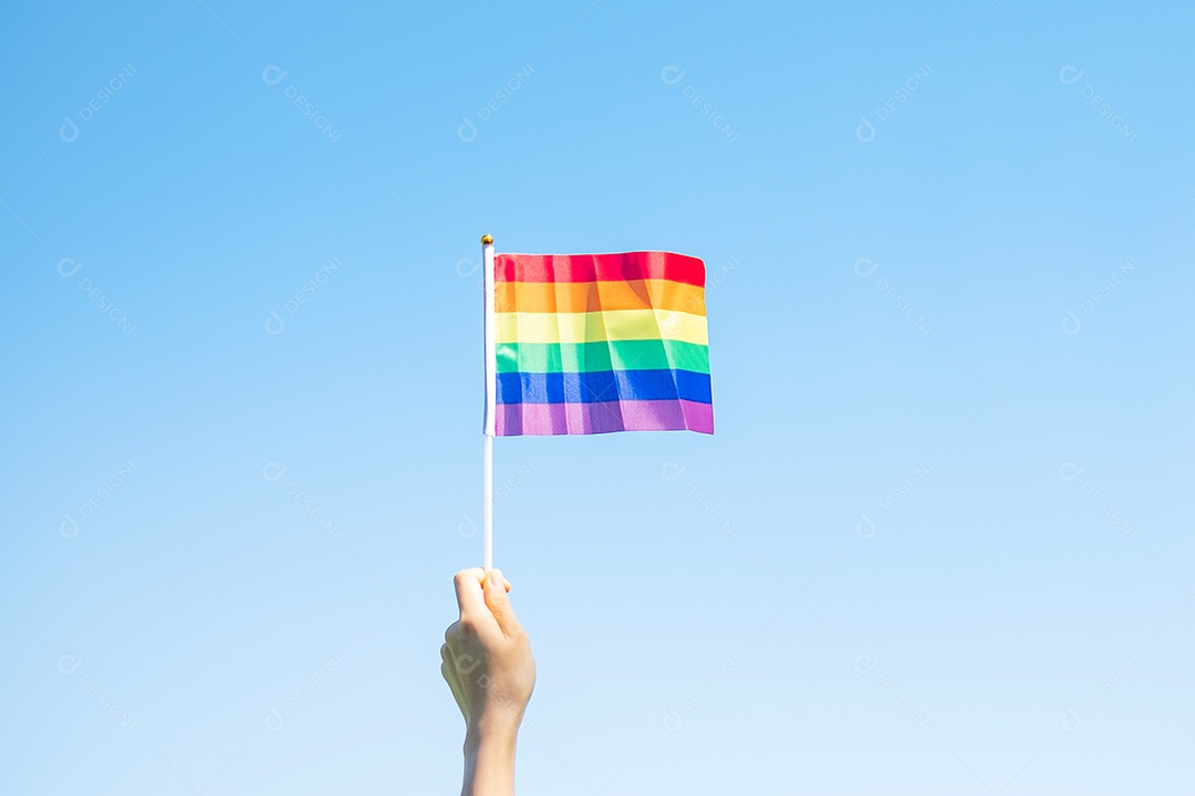 Mãos mostrando a bandeira LGBTQ Arco-íris no fundo da natureza.