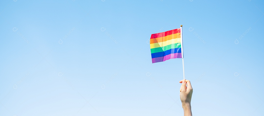 Mãos mostrando a bandeira LGBTQ  Arco-íris no fundo da natureza.