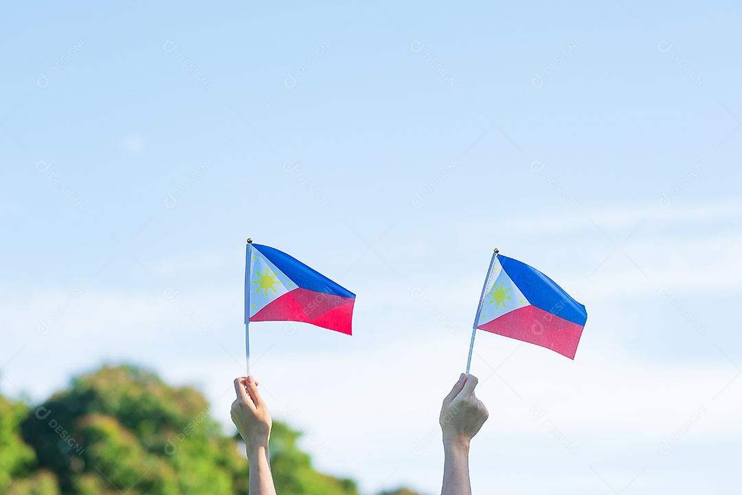 Mão segurando a bandeira das Filipinas no fundo da natureza. 12 de junho.