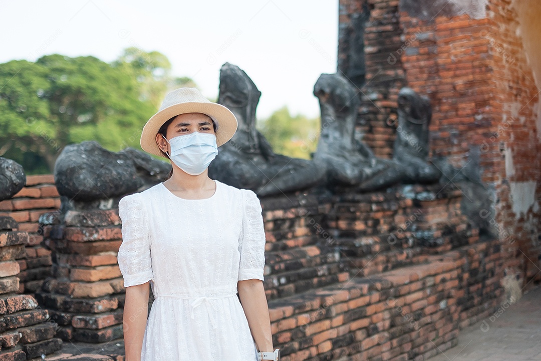 Mulher turista de vestido branco usando máscara cirúrgica
