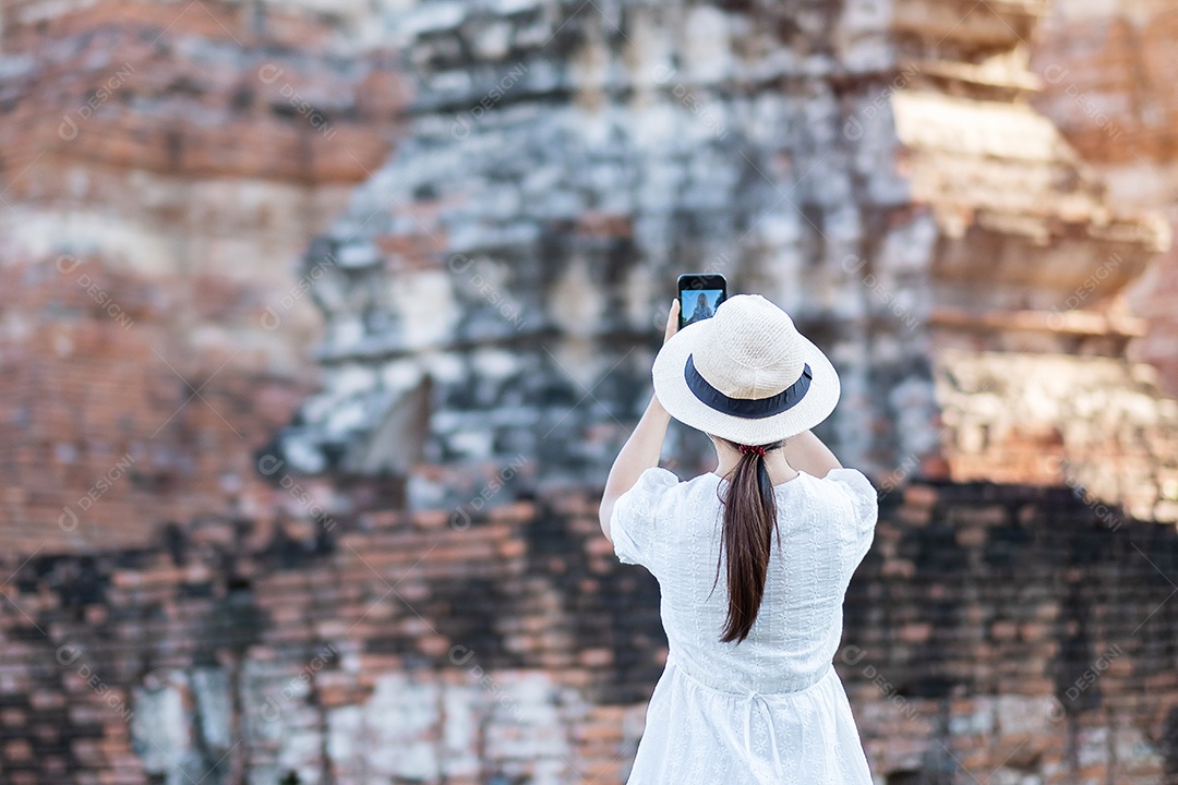 Mulher turista feliz em vestido branco tirando foto pelo smartphone móvel