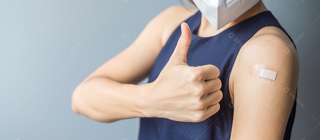 Mulher feliz mostrando o polegar com curativo depois de receber o covid 19