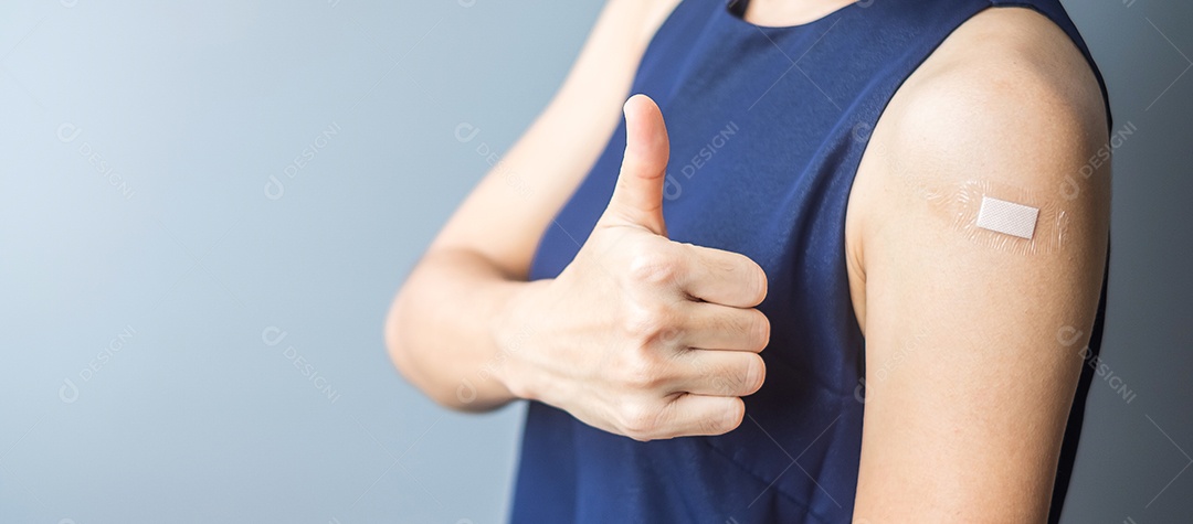 Mulher feliz mostrando o polegar com curativo depois de receber o covid 19